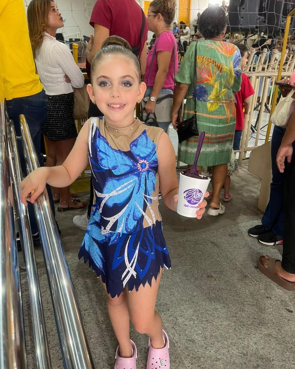 Ginasta com collant azul segurando um copo de açaí Bliss em campeonato de ginástica rítmica